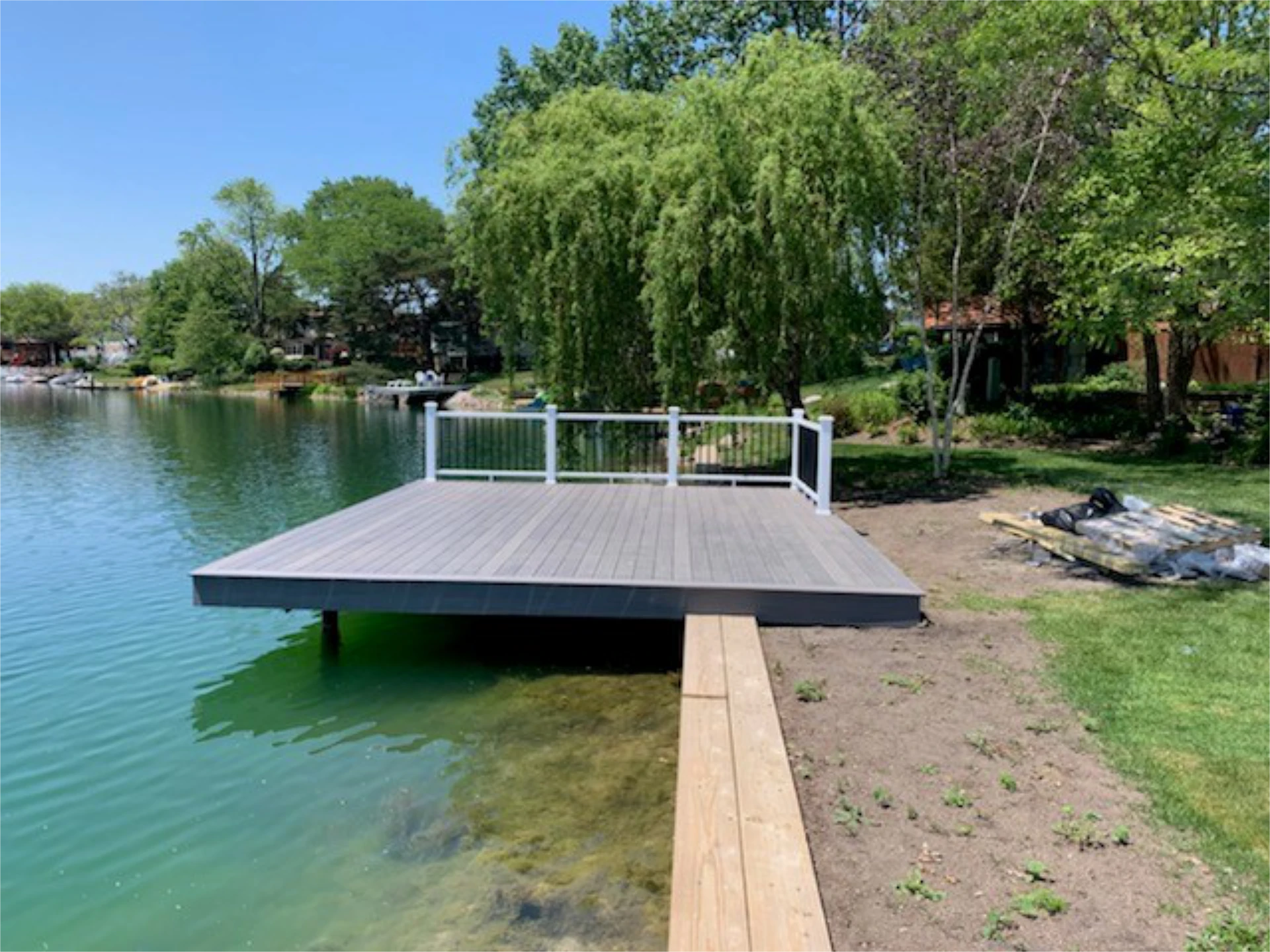 Pvc deck and dock with white and black railing featuring trees and lake on the background