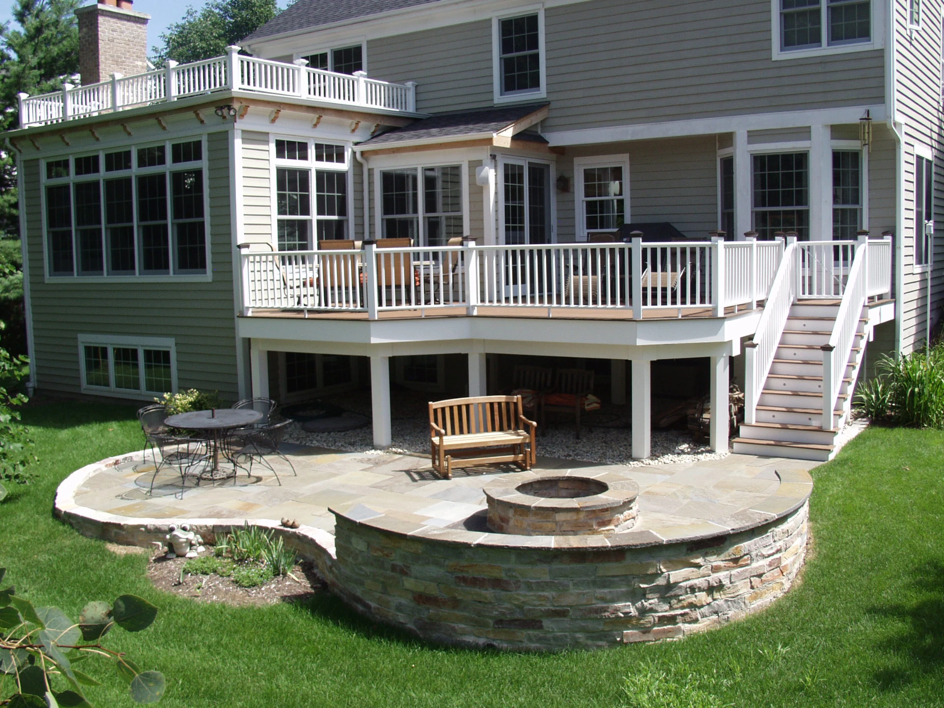 Stone patio and firepit and elevated pvc deck with white railing and sunroom attached in schaumburg il
