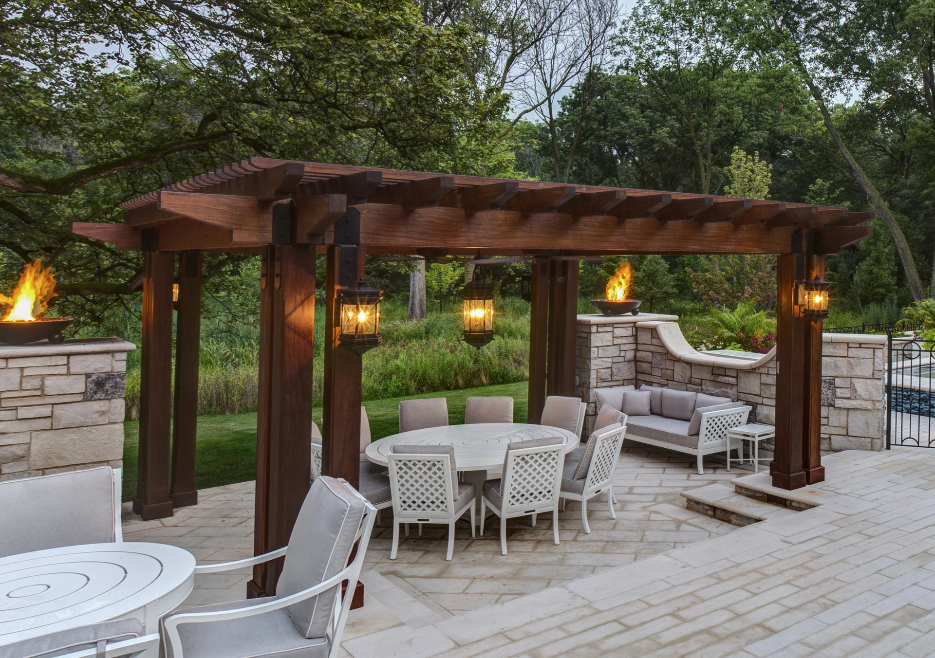 Tropical hardwood ipe pergola with glowing lanterns and gas fire bowls above stone patio in schaumburg il